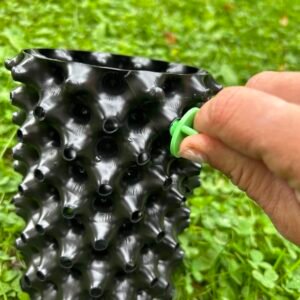 Plastový květináč se zvláštním designem na trávě.